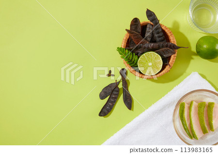 On the left side of the photography, full filled by ingredients from nature with black locust pod, lime, water and grapefruit. Space for advertising or displaying with high angle view 113983165