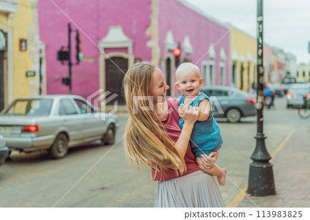 Mother and baby son tourists explore the vibrant streets of Valladolid, Mexico, immersing herself in the rich culture and colorful architecture of this charming colonial town 113983825