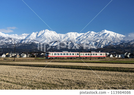A Toyama Chiho Railway train running with a view of Mount Tsurugi 113984086