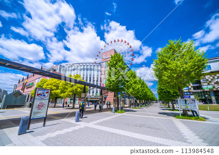Yokohama cityscape in April, Japan. View of the ferris wheel and Tsuzuki Hankyu Railway in front of Center Kita Station, shining against the fresh greenery and blue sky. 113984548