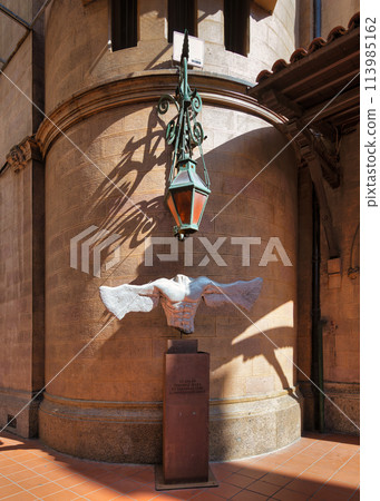 A sculpted dove in flight adorns the courtyard of St. Anthony of Padua Church under a hanging lantern 113985162