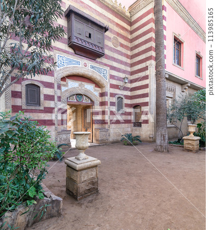 Striking red and white striped arched entrance leads into a Mamluk era style building 113985165