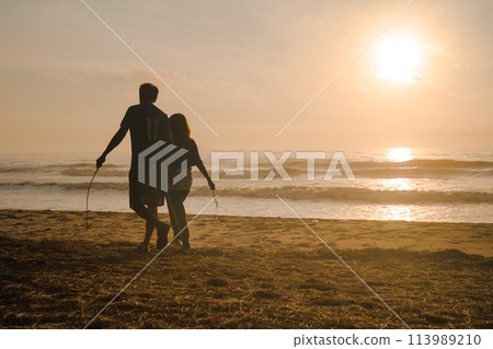 silhouette couple walk on beach with sunrise and sea background 113989210