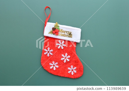 red wool winter sock on green background, christmas decoration red wool winter sock on green background, christmas decoration 113989639