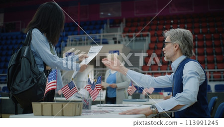 African American girl talks with polling officer and takes bulletin 113991245