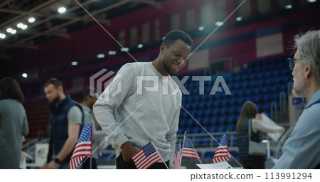 American citizens talks with polling officer and takes bulletin 113991294