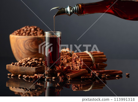 Coffee liquor is poured from a bottle into a glass. Coffee liquor is poured from a bottle into a glass. 113991318