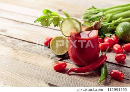 Bloody Mary cocktail garnished with gherkin, olive, lime, and celery. 113991363