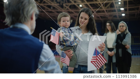 Woman with baby on hands talks with polling officer Woman with baby on hands talks with polling officer 113991386