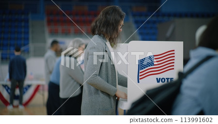 African American voter with bulletin in hands comes to booth 113991602