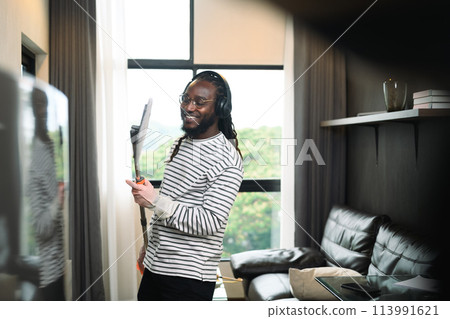 Attractive African American man enjoy doing housework, singing and dance with mop Attractive African American man enjoy doing housework, singing and dance with mop 113991621
