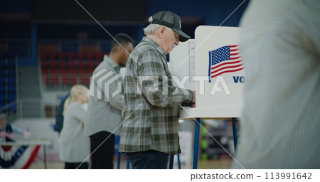 Elderly voter with bulletin in hands comes to voting booth 113991642
