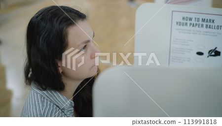 Female voter stands at voting booth in polling station 113991818