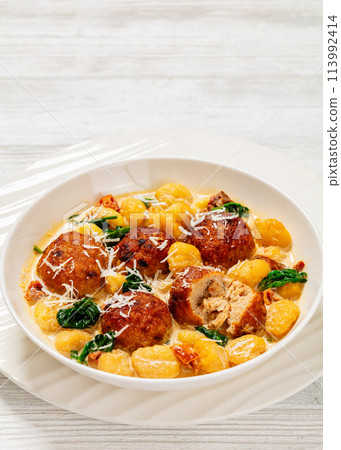 tuscan chicken meatballs with gnocchi in a bowl 113992414