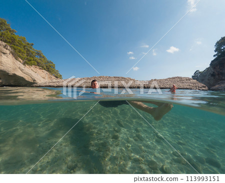 Young male on holidays enjoy floating on a crystal clear water beach of Antalya Turkey. Man swimming with open arms. Relax and tranquility 113993151