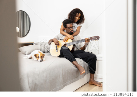 Relaxed Couple Enjoying Guitar Music With Adorable Dog 113994115