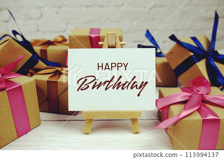 Happy Birthday text on paper card with gift box present on wooden background 113994137