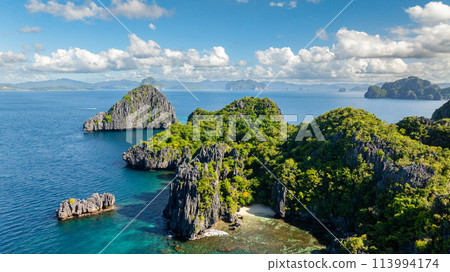 Islets and beach in Miniloc Island. Blue sky and clouds. El Nido, Philippines. Islets and beach in Miniloc Island. Blue sky and clouds. El Nido, Philippines. 113994174