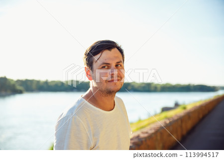 34 years old male on vacation in summer, sunny day on lake or river. Positive emotions, leisure activity, relax. walk along embankment waterfront, promenade 113994517