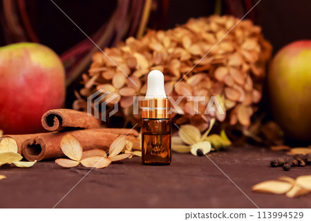 Cosmetic essential oil in gold glass bottle with pipette, cosmetology serum product for moisturizer facial care, apple, cinnamon on brown. skincare product blank package, mockup, mini travel version 113994529