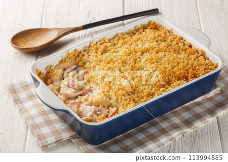 Chicken Cordon Bleu Casserole with chicken breast, chopped ham and Swiss cheese layered with creamy sauce and a buttery Panko breadcrumbs close up in the baking dish. Horizontal 113994885