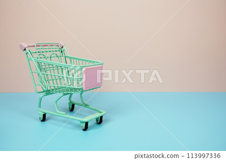Mini Trolley shopping cart with space for text on pink and blue background Mini Trolley shopping cart with space for text on pink and blue background 113997336