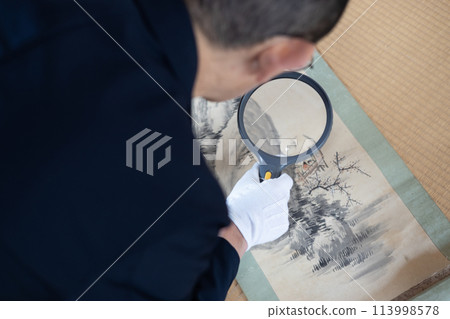 一名男工人正在鑑定舊掛軸 一名男工人正在鑑定舊掛軸 113998578