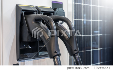 Close up of electric car charging station on the background of solar panels.. 113998834