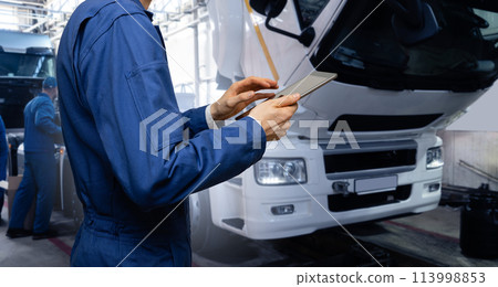 Serviceman with digital tablet on the background of the truck in the garage.. 113998853