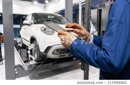 Serviceman with digital tablet on the background of the car in the car service Serviceman with digital tablet on the background of the car in the car service 113998862