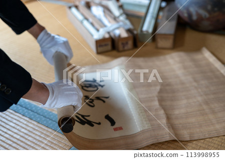 A man appraising an old hanging scroll A man appraising an old hanging scroll 113998955