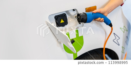 Woman holding plug of electric car charging station Woman holding plug of electric car charging station 113998995