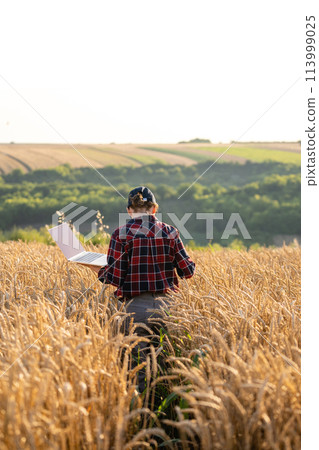 Woman farmer working with laptop on wheat field. Smart farming and digital agriculture Woman farmer working with laptop on wheat field. Smart farming and digital agriculture 113999025