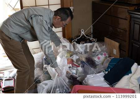 A man wearing work clothes sorting out unnecessary items 113999201