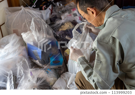 A man wearing work clothes sorting out unnecessary items 113999203