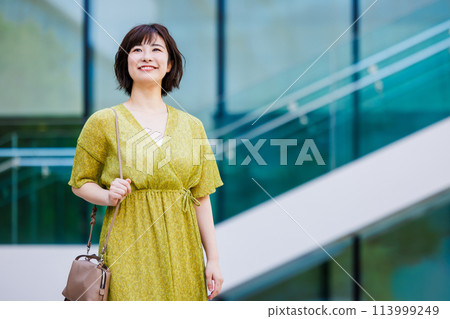 A young woman in a dress walking outdoors 113999249