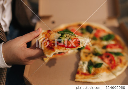 Close up of Woman open pizza box outdoors. Female hold open pizza box and smells appetizing 114000068