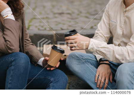 Smiling love couple sitting on the stairs outdoor and hold cup of coffee. Middle selection Smiling love couple sitting on the stairs outdoor and hold cup of coffee. Middle selection 114000076