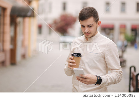 Middle selection of man stand in the city with cup of coffee and use phone Middle selection of man stand in the city with cup of coffee and use phone 114000082