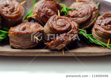 A plate of pieces of meat in the shape of roses with green herbs on top 114000496