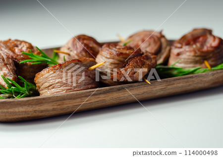 A plate of pieces of meat in the shape of roses with green herbs on top A plate of pieces of meat in the shape of roses with green herbs on top 114000498
