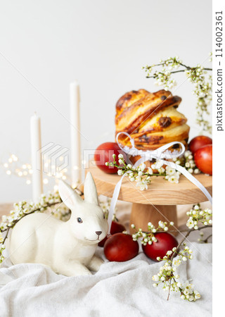 Festive table setting with ceramic bunny, red eggs, candles and Easter pastries, vertical photo. Easter holiday concept. Festive table setting with ceramic bunny, red eggs, candles and Easter pastries, vertical photo. Easter holiday concept. 114002361