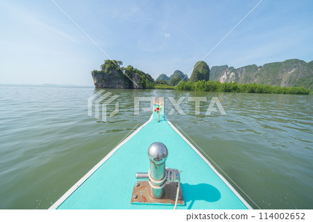 Sailing local wooden boat in the sea ocean and tree forest. Nature environment landscape background. Sailing local wooden boat in the sea ocean and tree forest. Nature environment landscape background. 114002652