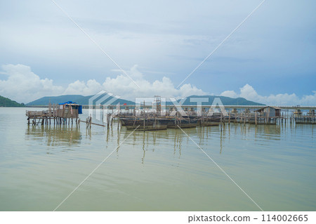 Fishing trap net in canal with fisherman urban city village town houses, lake or river. Nature landscape fisheries and fishing tools at Pak Pha, Songkhla, Thailand. Aquaculture farming Fishing trap net in canal with fisherman urban city village town houses, lake or river. Nature landscape fisheries and fishing tools at Pak Pha, Songkhla, Thailand. Aquaculture farming 114002665