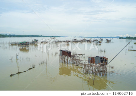 Fishing trap net in canal with fisherman urban city village town houses, lake or river. Nature landscape fisheries and fishing tools at Pak Pha, Songkhla, Thailand. Aquaculture farming 114002716