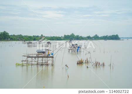 Fishing trap net in canal with fisherman urban city village town houses, lake or river. Nature landscape fisheries and fishing tools at Pak Pha, Songkhla, Thailand. Aquaculture farming Fishing trap net in canal with fisherman urban city village town houses, lake or river. Nature landscape fisheries and fishing tools at Pak Pha, Songkhla, Thailand. Aquaculture farming 114002722
