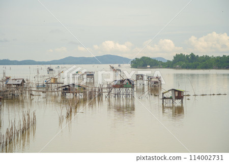 Fishing trap net in canal with fisherman urban city village town houses, lake or river. Nature landscape fisheries and fishing tools at Pak Pha, Songkhla, Thailand. Aquaculture farming Fishing trap net in canal with fisherman urban city village town houses, lake or river. Nature landscape fisheries and fishing tools at Pak Pha, Songkhla, Thailand. Aquaculture farming 114002731