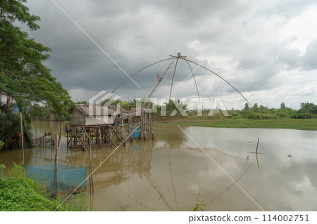 Fishing trap net in canal with fisherman urban city village town houses, lake or river. Nature landscape fisheries and fishing tools at Pak Pha, Songkhla, Thailand. Aquaculture farming Fishing trap net in canal with fisherman urban city village town houses, lake or river. Nature landscape fisheries and fishing tools at Pak Pha, Songkhla, Thailand. Aquaculture farming 114002751