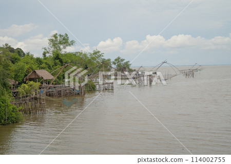 Fishing trap net in canal with fisherman urban city village town houses, lake or river. Nature landscape fisheries and fishing tools at Pak Pha, Songkhla, Thailand. Aquaculture farming Fishing trap net in canal with fisherman urban city village town houses, lake or river. Nature landscape fisheries and fishing tools at Pak Pha, Songkhla, Thailand. Aquaculture farming 114002755