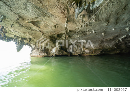 Natural stalactite and stalagmite rock stone cliff hang from cave ceiling in cave with lake river sea. Environmental explore. Landscape background. Erosion Natural stalactite and stalagmite rock stone cliff hang from cave ceiling in cave with lake river sea. Environmental explore. Landscape background. Erosion 114002937